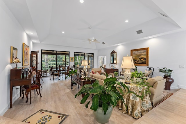 living room featuring light hardwood / wood-style flooring, a raised ceiling, and ceiling fan