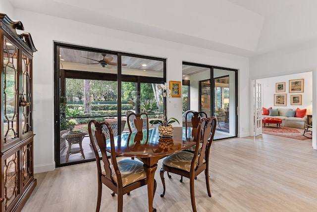 dining area with ceiling fan, light hardwood / wood-style flooring, and vaulted ceiling