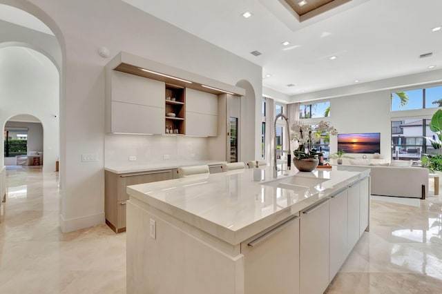 kitchen with light stone countertops and a large island with sink