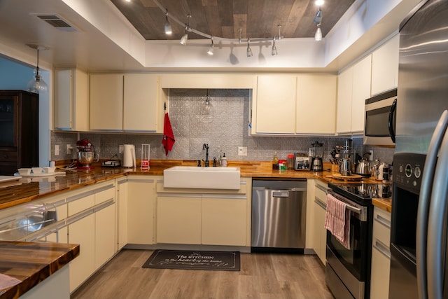 kitchen with wooden counters, track lighting, sink, light hardwood / wood-style flooring, and appliances with stainless steel finishes