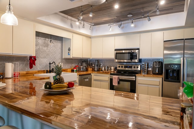 kitchen featuring rail lighting, sink, hanging light fixtures, butcher block countertops, and stainless steel appliances