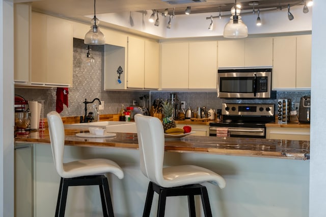 kitchen with wooden counters, appliances with stainless steel finishes, tasteful backsplash, decorative light fixtures, and white cabinetry