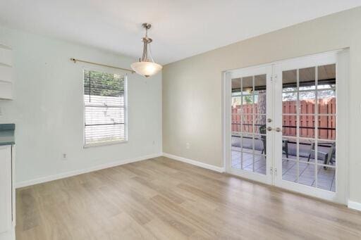 unfurnished dining area with plenty of natural light, french doors, and light wood-type flooring