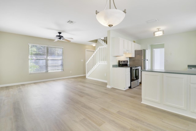 kitchen featuring light wood-type flooring, stainless steel appliances, white cabinetry, and hanging light fixtures