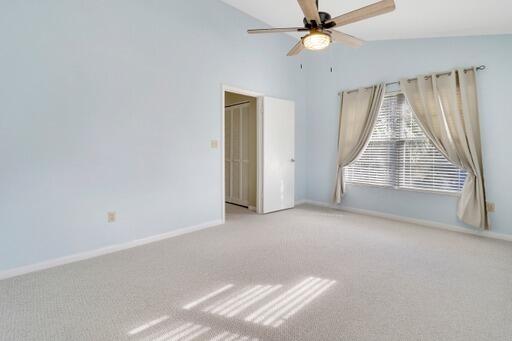 carpeted spare room with ceiling fan and lofted ceiling