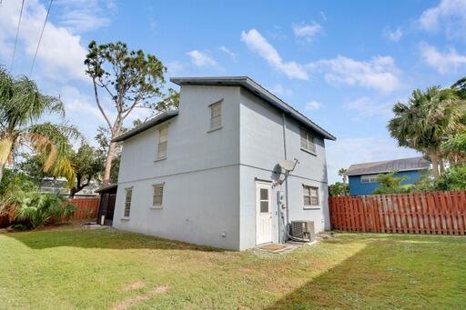 back of property with cooling unit and a yard