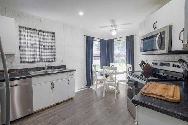 kitchen with hardwood / wood-style floors, sink, white cabinets, and stainless steel appliances