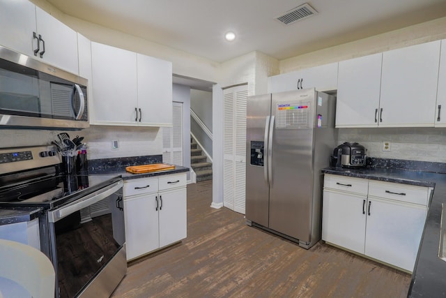 kitchen with decorative backsplash, white cabinets, stainless steel appliances, and dark hardwood / wood-style floors