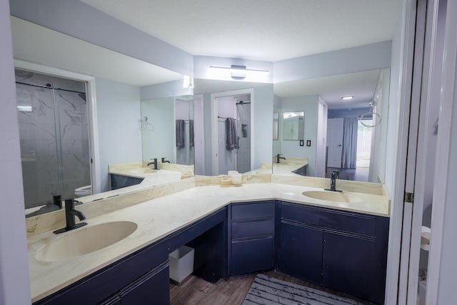 bathroom with vanity, toilet, wood-type flooring, and a tile shower