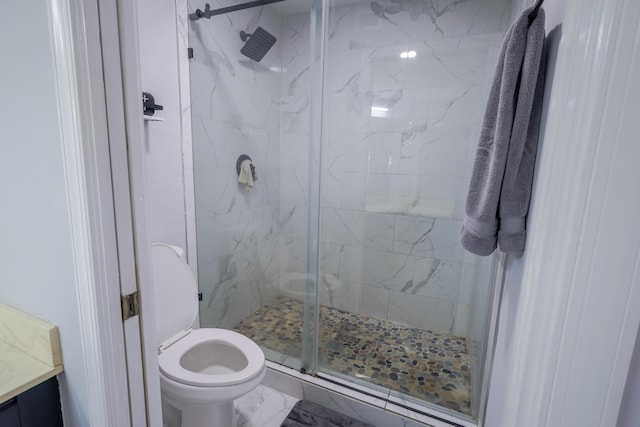 bathroom featuring a shower with door, vanity, and toilet