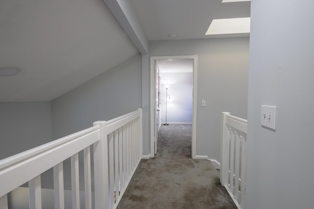 hallway with carpet floors and lofted ceiling with skylight