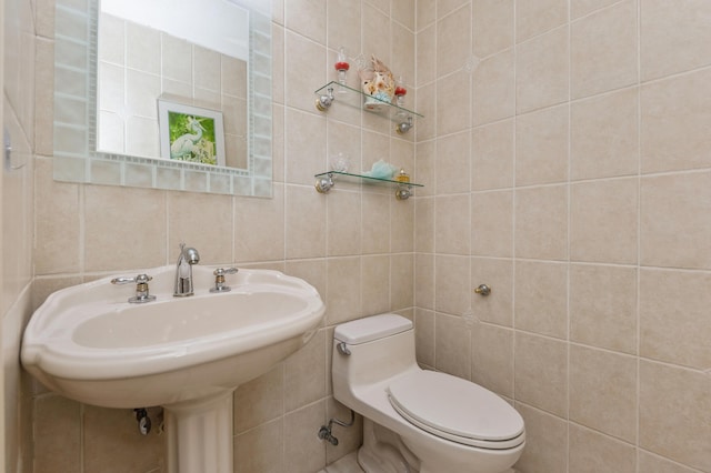 bathroom featuring tile walls, sink, and toilet