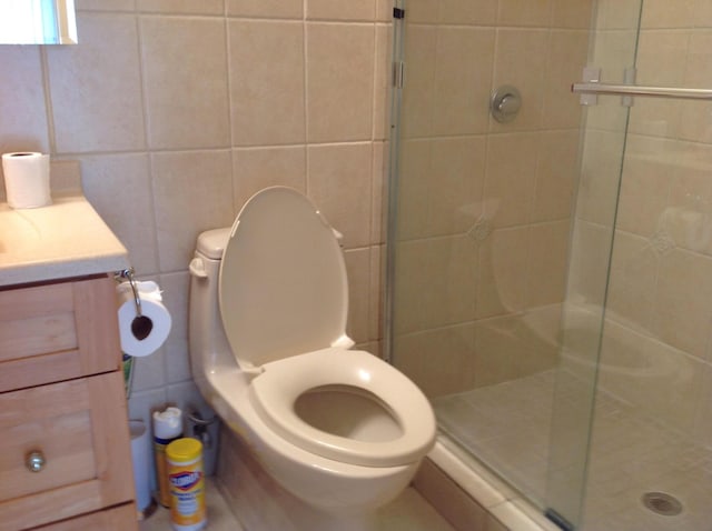 bathroom with vanity, toilet, an enclosed shower, and tile walls