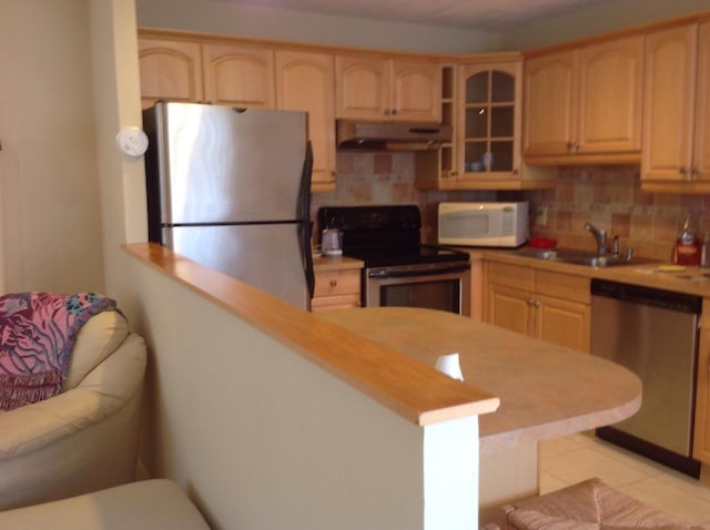 kitchen featuring sink, light tile patterned floors, kitchen peninsula, stainless steel appliances, and backsplash