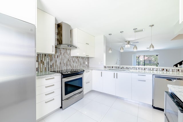 kitchen with white cabinets, pendant lighting, stainless steel appliances, and wall chimney exhaust hood