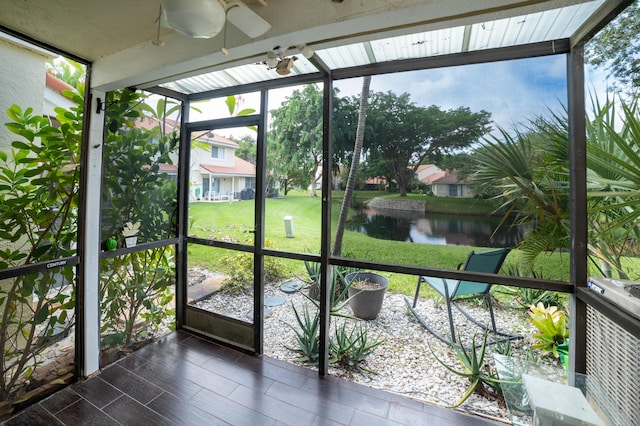 unfurnished sunroom with ceiling fan and a water view