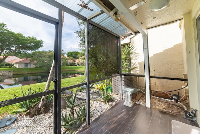 unfurnished sunroom with ceiling fan and a water view