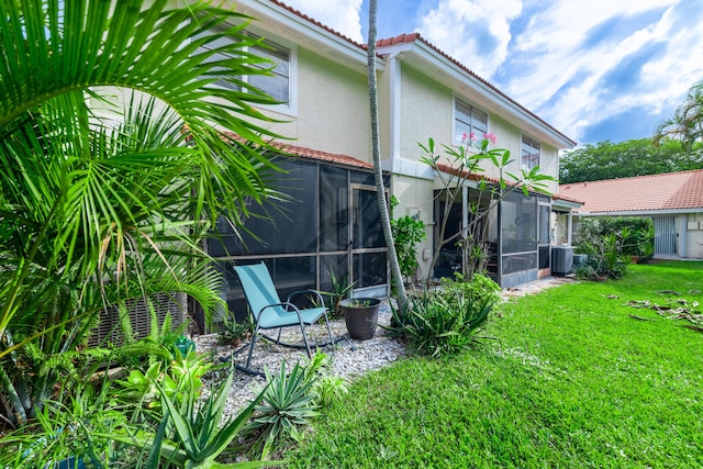 back of property with a sunroom and a lawn