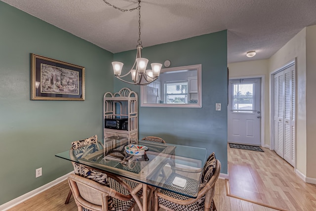 dining room featuring a textured ceiling, light wood-type flooring, and an inviting chandelier