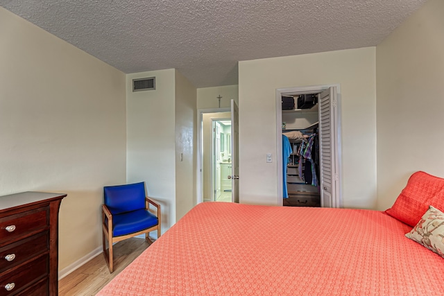 bedroom featuring a closet, light hardwood / wood-style floors, and a textured ceiling