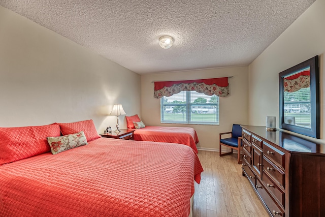 bedroom with light wood-type flooring and a textured ceiling