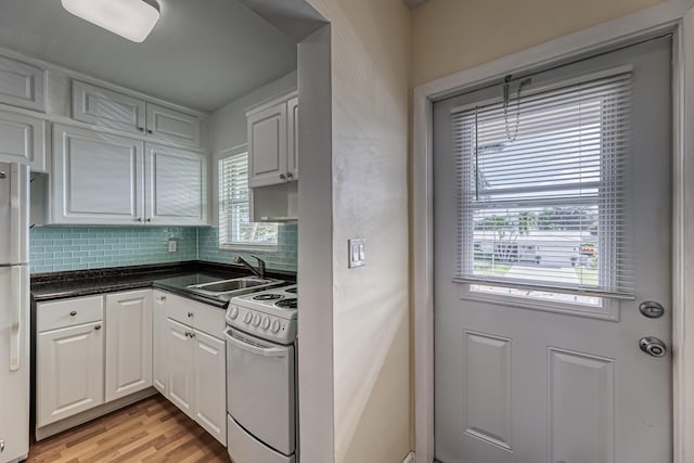 kitchen with white appliances, white cabinets, sink, light hardwood / wood-style flooring, and tasteful backsplash