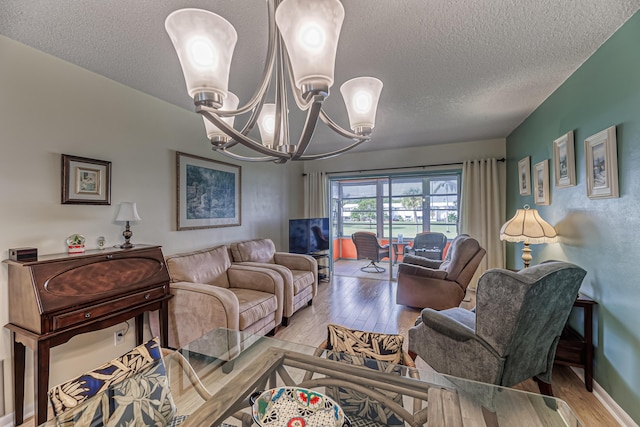 living room with a textured ceiling, light wood-type flooring, and a notable chandelier