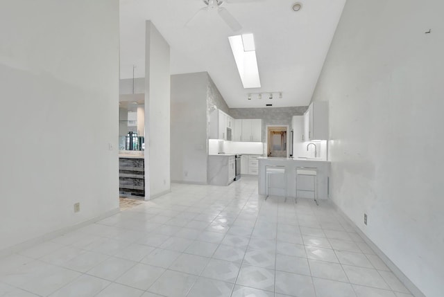 living room with rail lighting, a skylight, sink, and light tile patterned floors