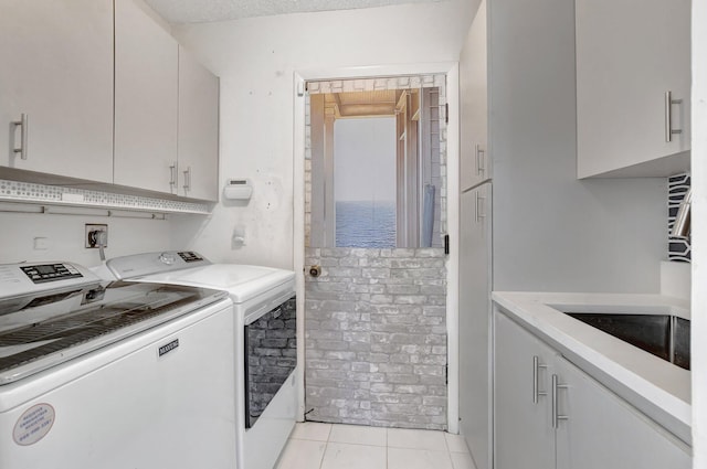 washroom with light tile patterned floors, washing machine and dryer, and cabinets