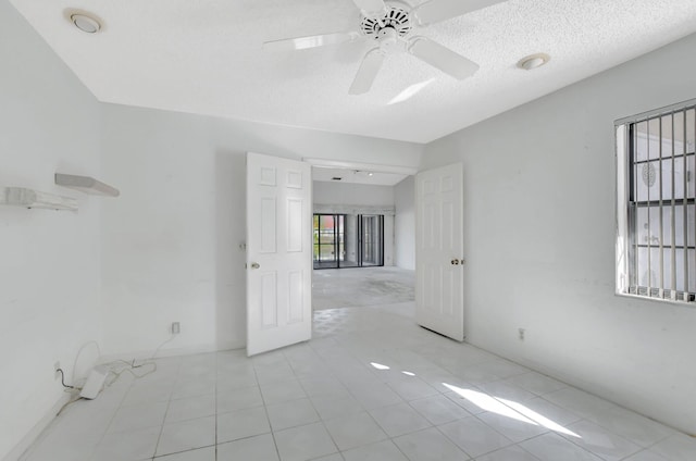 unfurnished room with ceiling fan and a textured ceiling