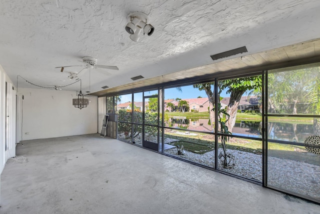 unfurnished sunroom with ceiling fan and a water view