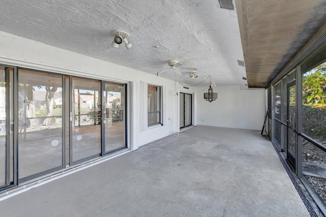 unfurnished sunroom featuring ceiling fan and plenty of natural light