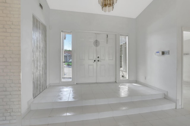 foyer featuring light tile patterned floors and brick wall