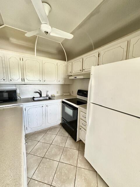 kitchen featuring sink, white cabinets, black appliances, and light tile patterned floors