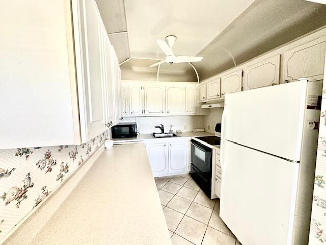 kitchen featuring black appliances, white cabinets, sink, ceiling fan, and light tile patterned floors