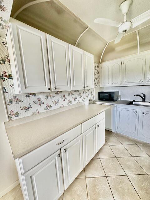 kitchen with light tile patterned floors, white cabinetry, ceiling fan, and sink