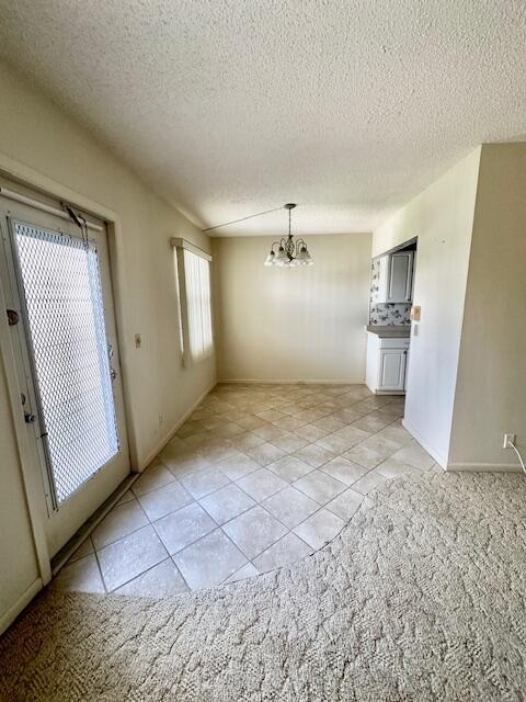 interior space with light tile patterned floors, a textured ceiling, and an inviting chandelier