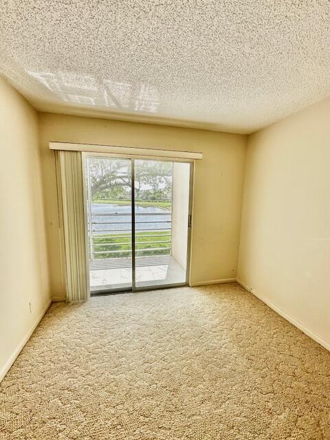 unfurnished room with carpet, a textured ceiling, and a water view