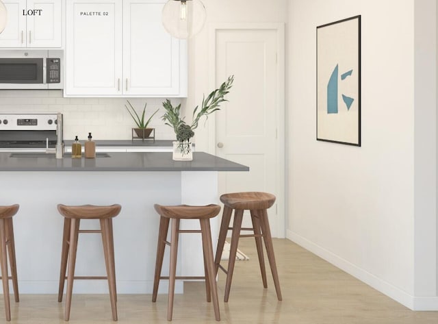 kitchen featuring range, backsplash, white cabinetry, and a kitchen breakfast bar