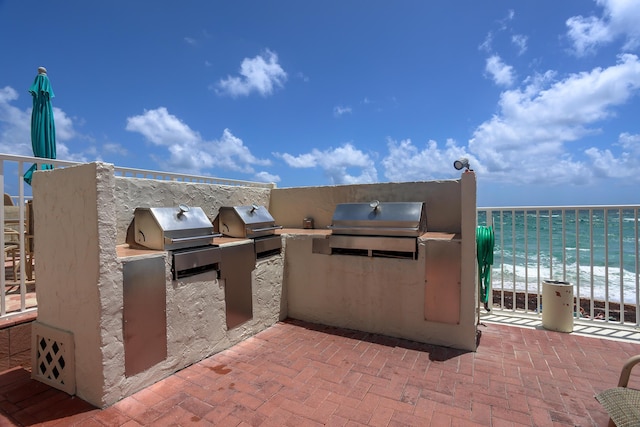 view of patio featuring area for grilling, a water view, and a view of the beach