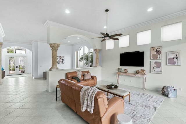 tiled living room with ceiling fan, a healthy amount of sunlight, ornate columns, and ornamental molding