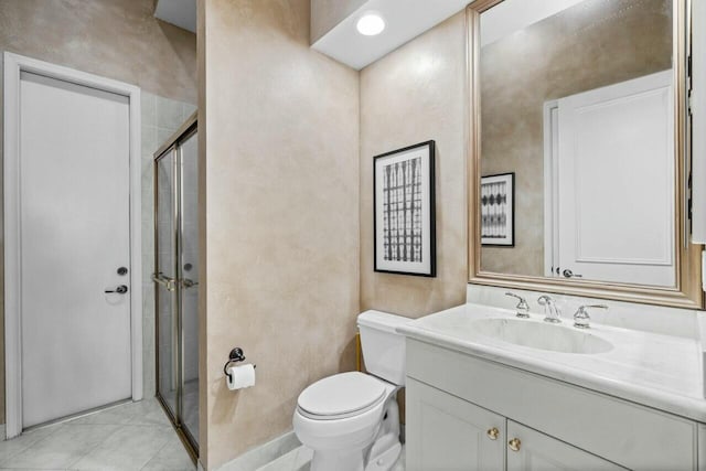 bathroom with tile patterned floors, vanity, an enclosed shower, and toilet