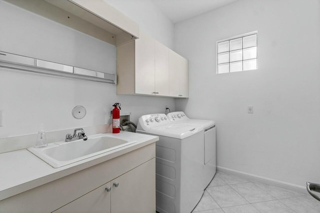 washroom with washing machine and clothes dryer, sink, light tile patterned floors, and cabinets