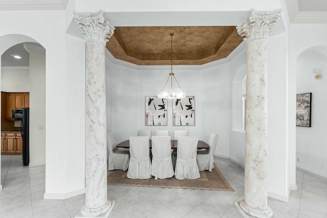 tiled dining area featuring a tray ceiling, ornate columns, ornamental molding, and an inviting chandelier