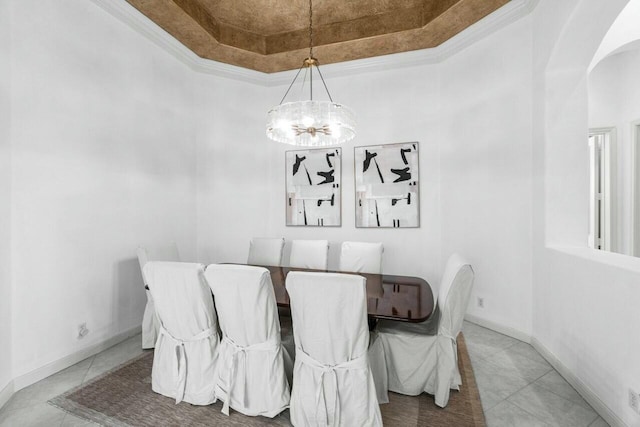 dining space featuring a tray ceiling, crown molding, tile patterned floors, and an inviting chandelier