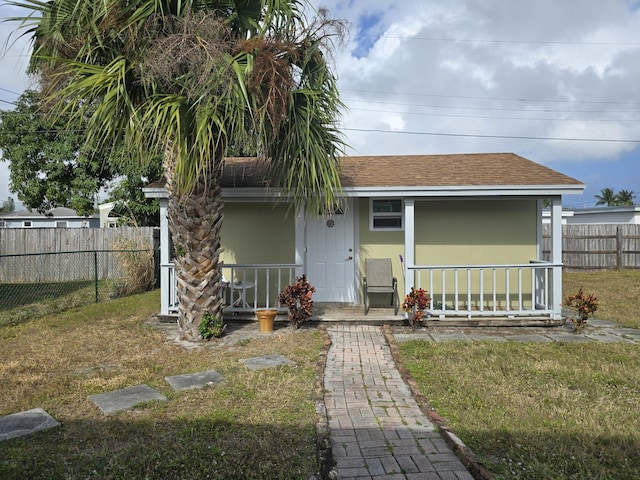 rear view of house featuring a lawn and a porch