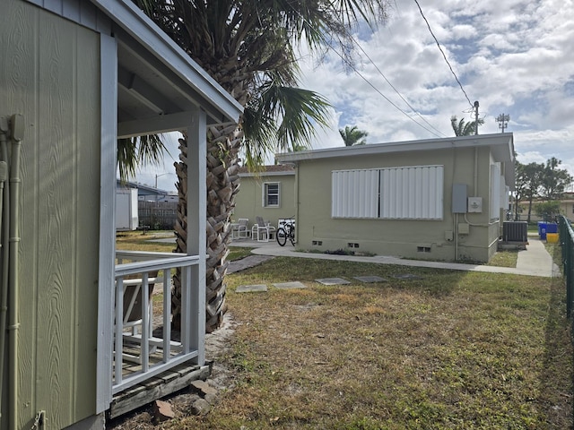 view of side of property featuring a patio area, a yard, and cooling unit