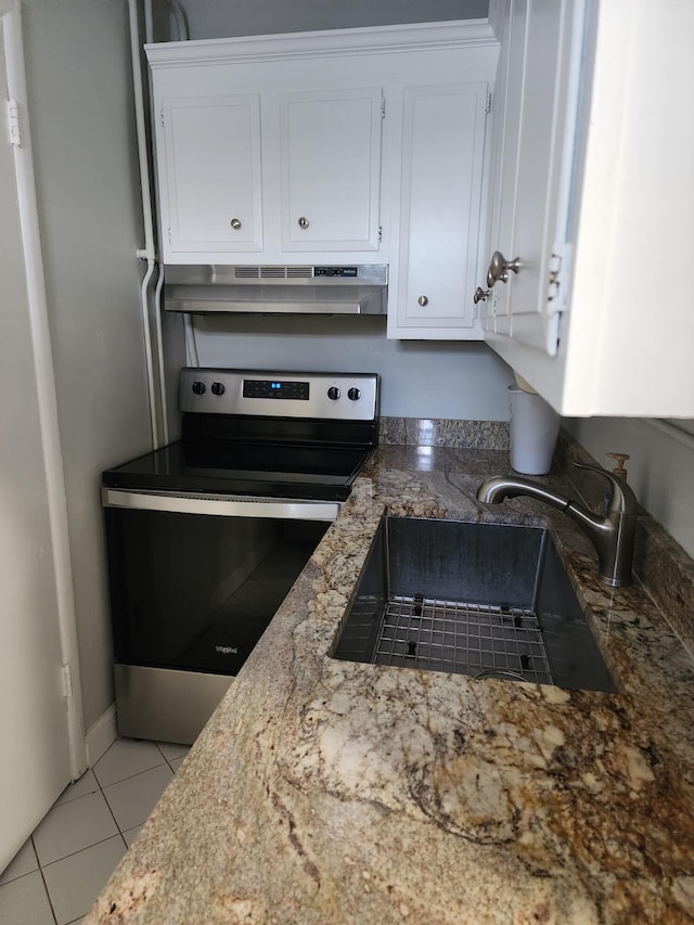 kitchen with stainless steel electric stove, white cabinetry, sink, and light tile patterned floors