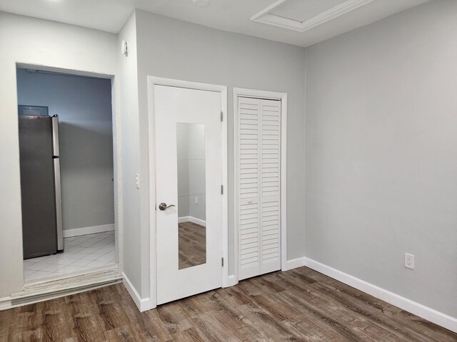 unfurnished bedroom with stainless steel refrigerator, a closet, and wood-type flooring