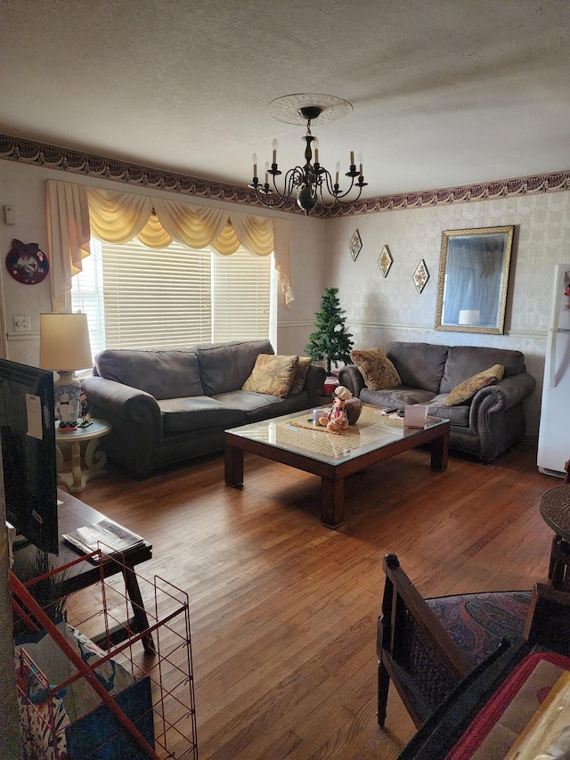 living room with a chandelier, a textured ceiling, and hardwood / wood-style flooring